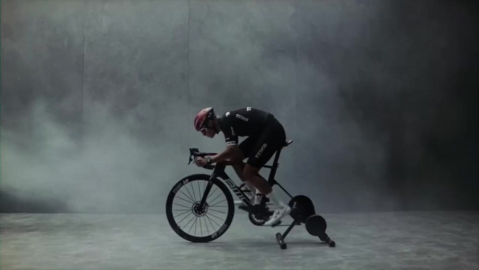 Cycliste en position aéro sur vélo BMC Tudor dans la fumée — Oakley Speed Takes Time